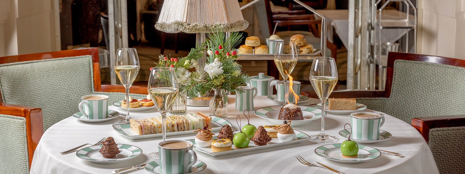 Afternoon Tea assortment of sandwiches and cakes served on a table with glasses of champagne.