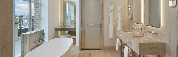 Bathroom with floor to ceiling glass windows, freestanding bathtub and his and her sinks